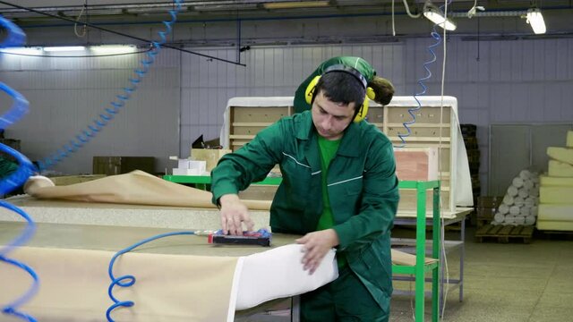 Workers dressed in uniform make a sofa, couch or settee in a furniture factory. 4K
