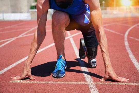 Adaptive sportsman with prosthetic foot at the start of running track
