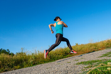 Fototapeta premium young caucasian fitness woman runs up the countryside road.