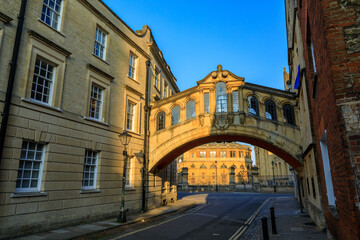 Hertford Bridge, Bridge of Sighs, in Oxford at sunrise with Sheldonian Theatre behind it and no people around, early in the morning on a clear day with blue sky. Oxford, England, UK.