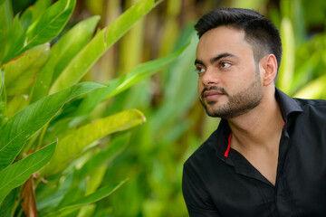 Young handsome bearded Indian businessman at the park