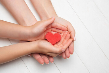 Human hands holding, giving heart isolated on white wooden background. Concept of emotions,...