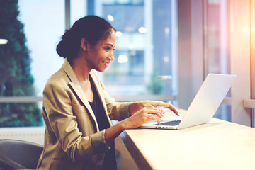 Smiling skilled female afro american administrative manager of corporation making online banking...