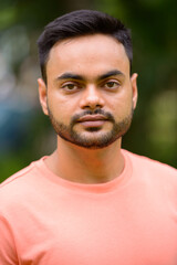 Fototapeta premium Young handsome bearded Indian man at the park