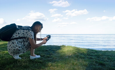 Side view portrait of woman taking picture in the background of beautiful seascape using a smartphone at sunset