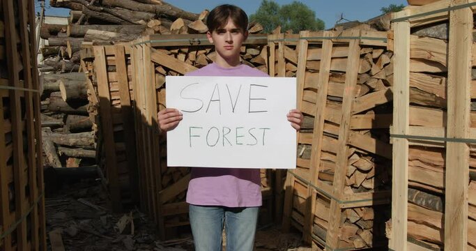 Outdoor of men activist with Save the forest ecology poster. In background chopped trees