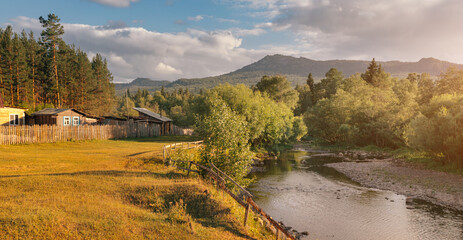 Obraz premium Panoramic landscape of taiga forest and a low mountain or hill. Small farm house near wild clean river