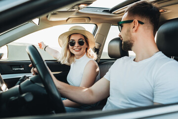 Happy Young Couple Sitting Inside Their Car and Enjoying Road Trip, Travel and Adventure Concept