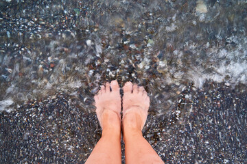 Top view of feet at the beach with sea waves. Grounding concept. connecting to nature