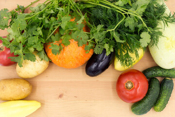 Fresh vegetables on a wooden cutting board, closeup: Pumpkin, potatoes, green onions, dill, tomato, parsley. Healthy food, vegan food.