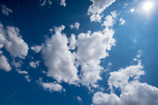 blue sky with clouds and sun, photographed upwards for backgrounds