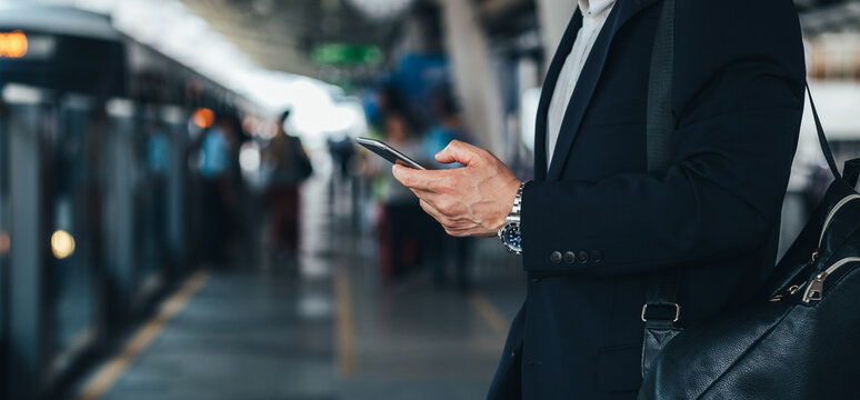 Man hands holding phone at train station stock photo