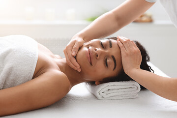 Obraz na płótnie Canvas African american woman enjoying healthy head massage at spa