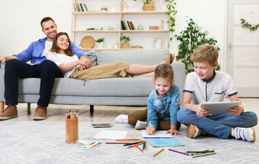 Happy Parents Relaxing While Kids Playing At Home