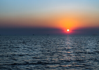 Fototapeta premium Beautiful sunset over a calm sea with a blue and orange glowing sky. Space for text, Selective focus. 