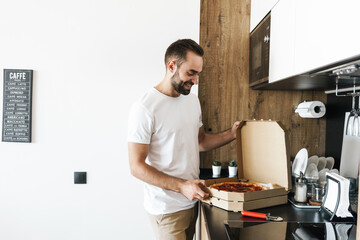 Cheerful happy man indoors at home with pizza