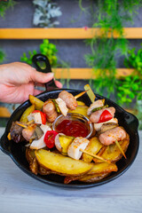 Fototapeta na wymiar Pentolaccia con spiedini di carne e verdure cotti alla griglia con contorno di patate al forno 