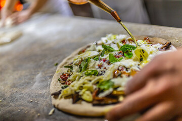 Pizzaiolo mentre condisce una pizza napoletana con l'olio 