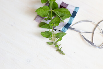 Cotton sachet bag with dry mint and fresh herb on white wooden background