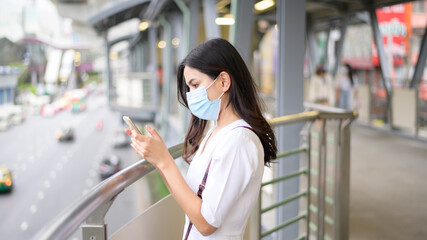A young woman is wearing face mask in the Street city .