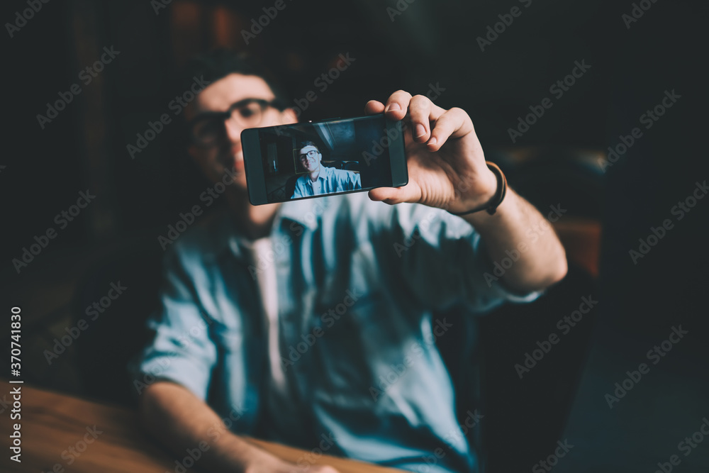 Poster selective focus on male hand with screen on smartphone device on blurred background, hipster guy tak