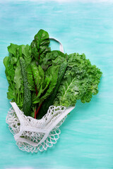 Chard, arugula and kale in mesh bag against hte green background. Top view
