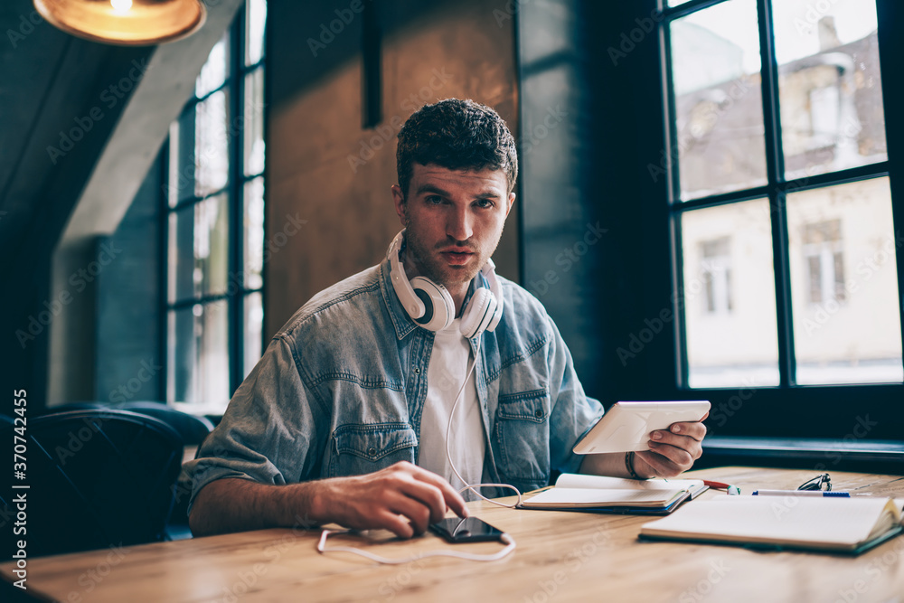 Poster portrait of handsome millennial man with modern gadget in hand using touch pad for sharing multimedi