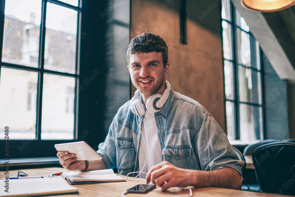 Aufkleber portrait of cheerful hipster guy with touch pad in hand looking at camera while installing media app