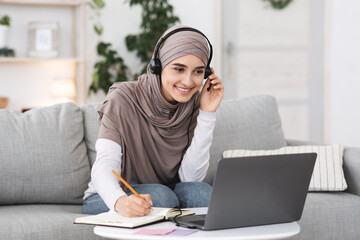 Online Education. Smiling Arabic Gir Watching Webinar On Laptop At Home