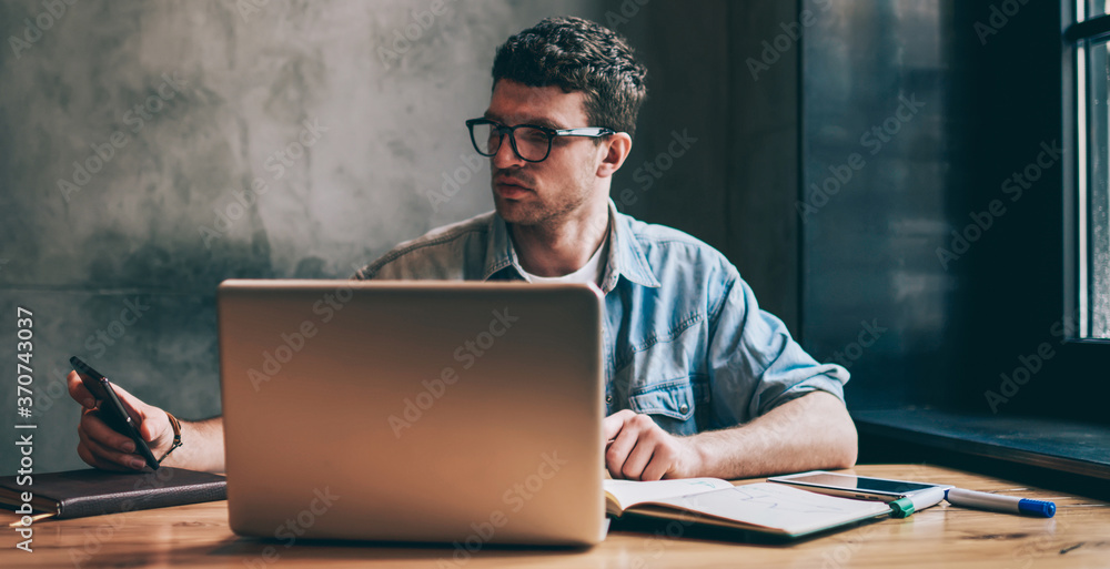 Aufkleber handsome male it professional checking time on smartphone device and updating notification indoors, 