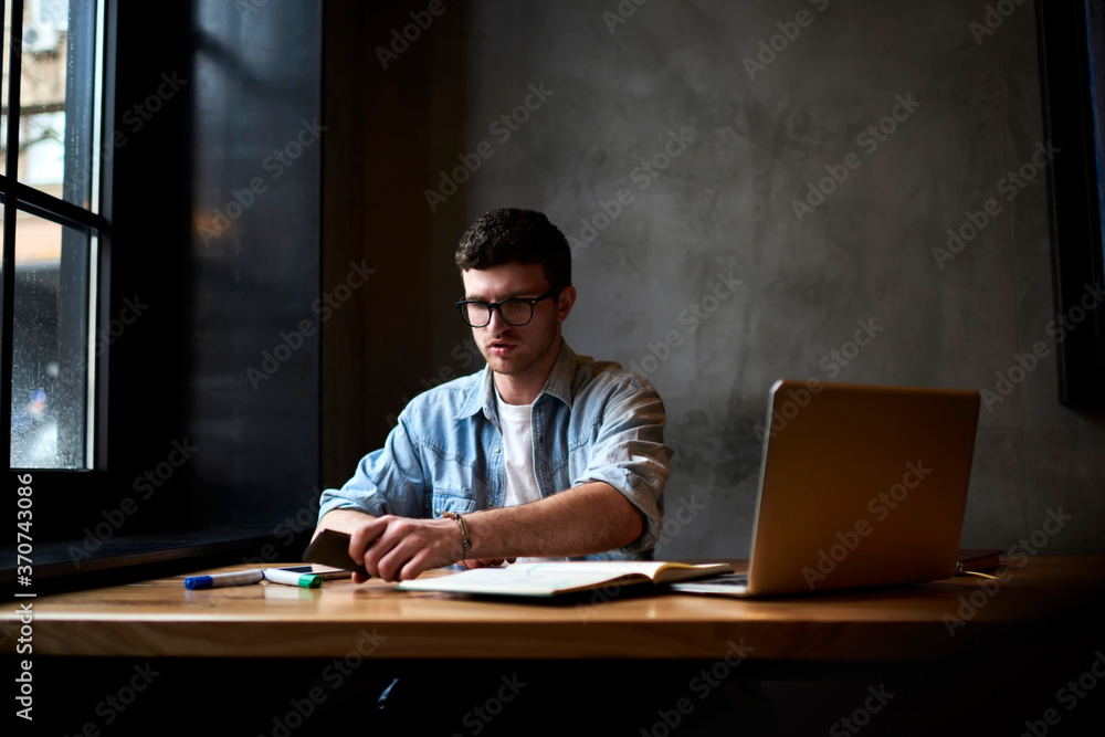 Poster professional designer dressed in denim shirt holding telephone in hand while working on new graphic 