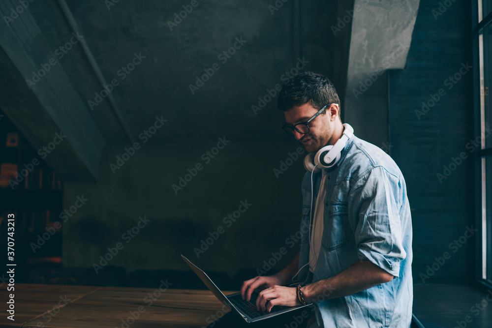 Poster happy positive hipster guy communicated in social networks using high wifi connection on new laptop 