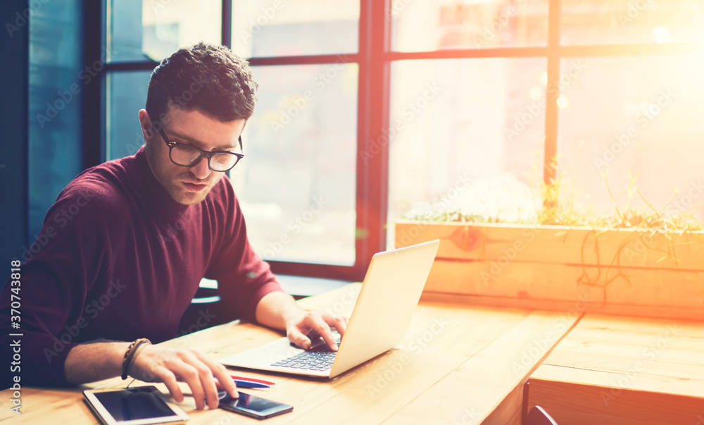 Poster concentrated professional it developer in stylish eyeglasses checking notification on smartphone whi