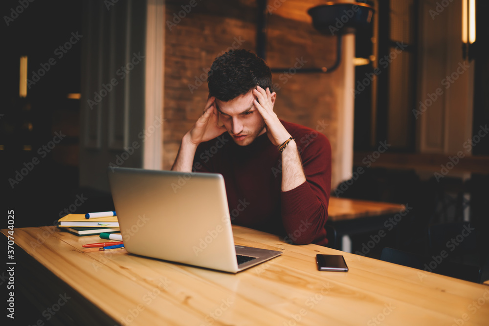 Poster man journalist working on netbook connected to free wireless connection in coworking space