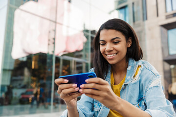 Young smiling casual african woman using mobile phone