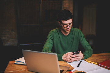 Young guy recreating during break in university sitting in campus with laptop computer