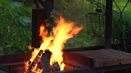 Summer cookout in patio of countryside cottage. Old burned grill graters hanging in background.