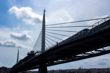 View of the metro and people passing over the Halic Metro Bridge.
