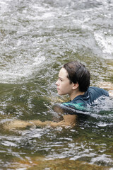An elementary school boy was having fun playing in the fast flowing stream at Kiriwong village. Khiri Wong village is a famous village of natural tourism in Thailand.