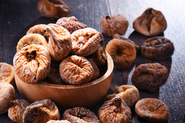 Composition with bowl of dried figs on wooden table