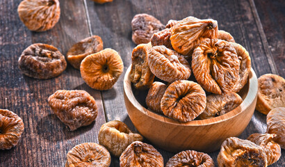 Composition with bowl of dried figs on wooden table