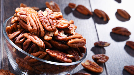 Bowl with pecan nuts on wooden table.
