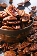 Bowl with pecan nuts on wooden table.