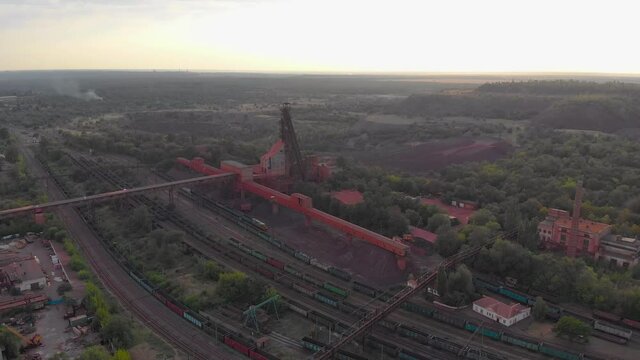 Industrial mining quarry red iron ore headframe aerial drone takeoff up camera movement Krivoy Rog Ukraine