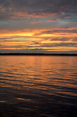 Obraz premium Gorgeous, calm sunset from Canadian lake with vast colours in the clouds and lake showing pinks, golds, oranges and teals.