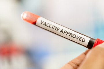 hand holding a tube of Vaccine Approved 