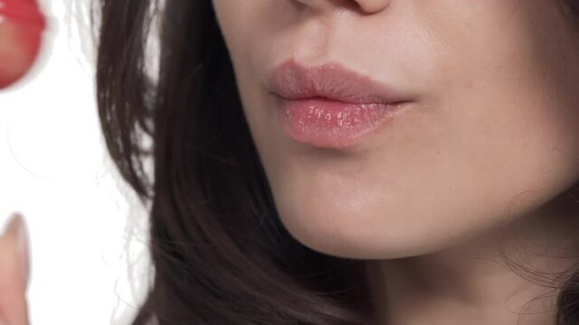 Masco shot of lower face of Caucasian woman sucking and licking lollypop.