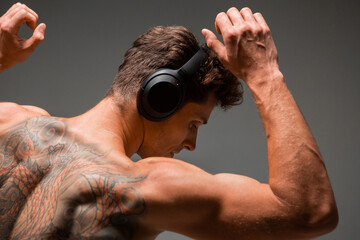 Cool young guy in wireless headphone listen to song and dance without shirt. Music and dance...
