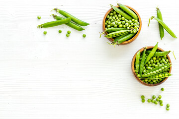 Set of green pea pods in wooden bowl on kitchen table desk