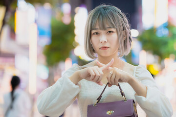 夜の繁華街で、NGサインをする女性